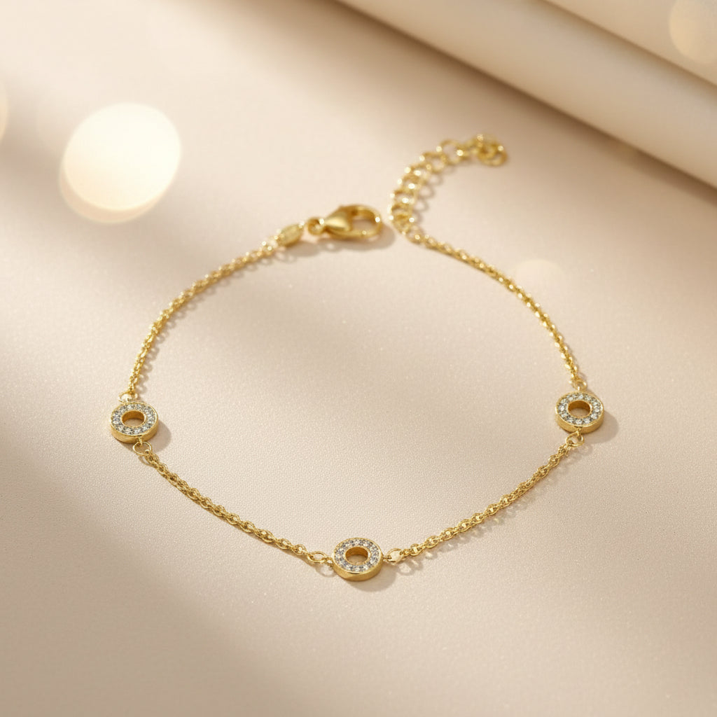 Feines Armband aus vergoldetem 925er Silber mit drei runden Elementen, die umlaufend mit klaren Zirkonia-Steinen besetzt sind, plus Verlängerungskettchen und Karabinerverschluss.