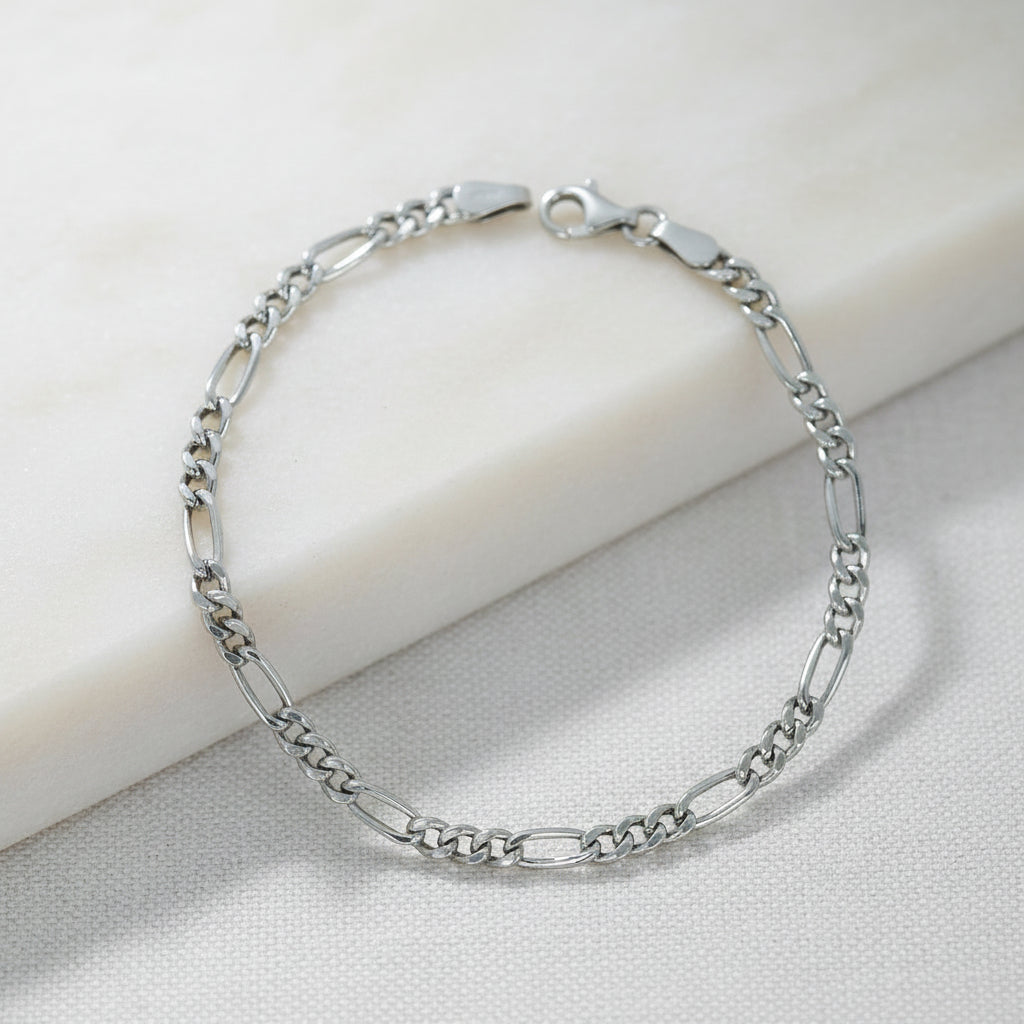 Armband aus rhodiniertem 925er Silber im Figaro-Kettendesign mit abwechselnd langen und kurzen Gliedern sowie Karabinerverschluss.