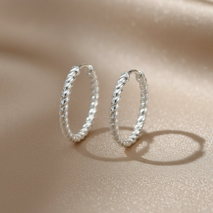 Zarte Creolen aus rhodiniertem 925er Silber mit rundumlaufender, gedrehter Struktur.