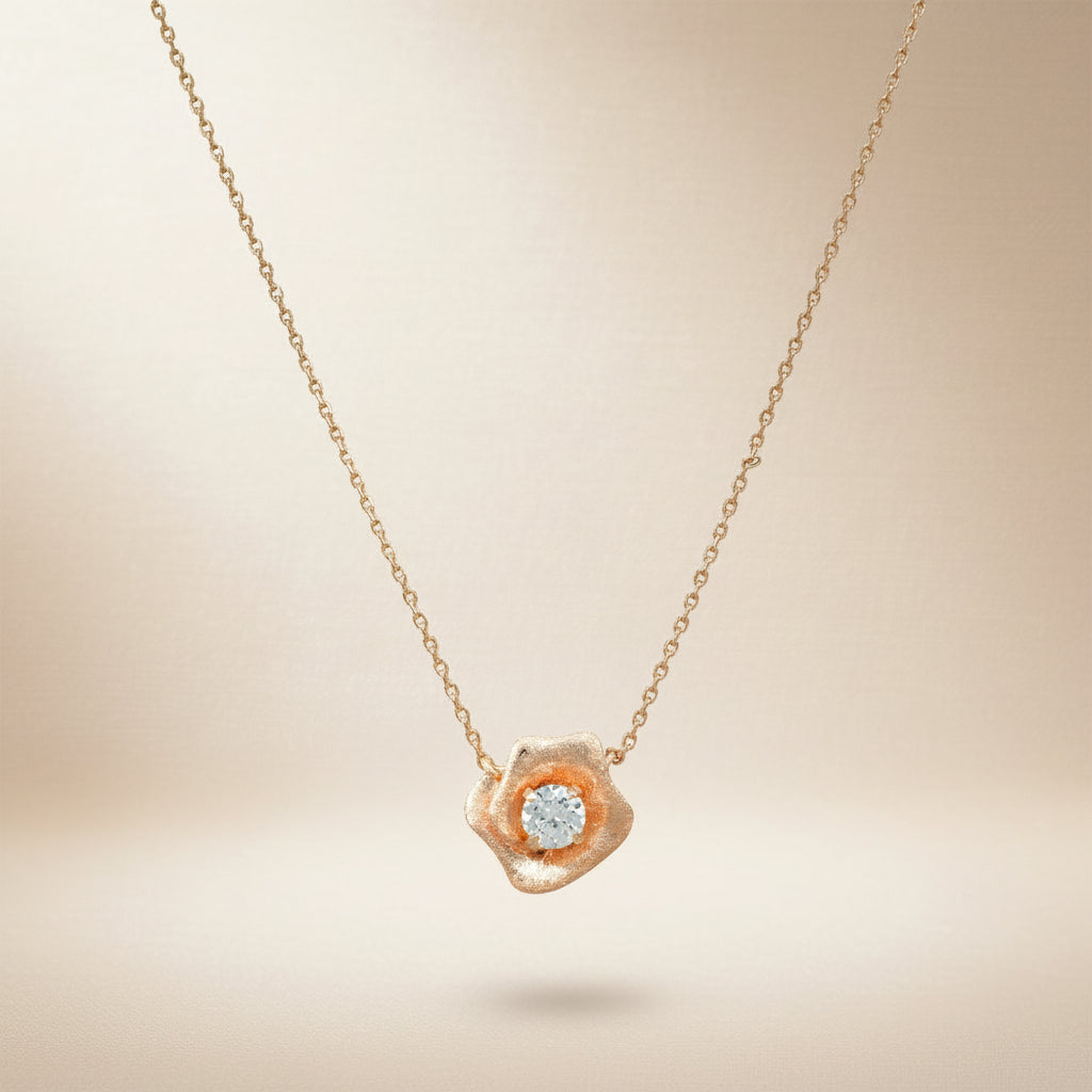 Feine Kette in Roségold-Optik mit kleinem, organisch geformtem Blütenanhänger und mittig gefasstem, klar funkelndem Zirkonia-Stein.