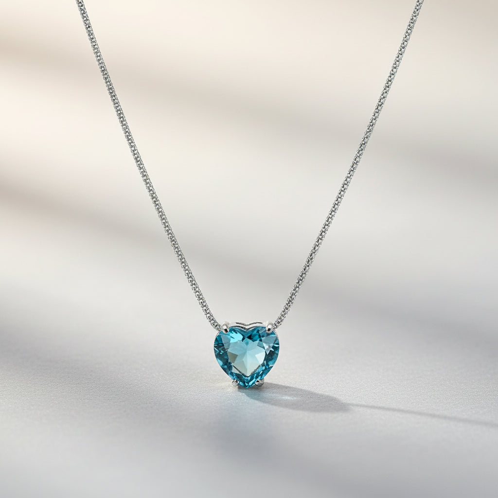 Feine Silberkette mit mittig gefasstem, herzförmigem Blautopas in Krappenfassung.