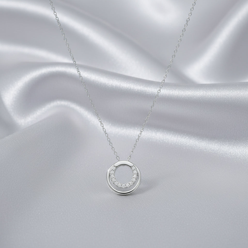 Feine Silberkette mit rundem Anhänger, dessen innere Unterhälfte halbkreisförmig mit klaren Zirkonia-Steinen besetzt ist.