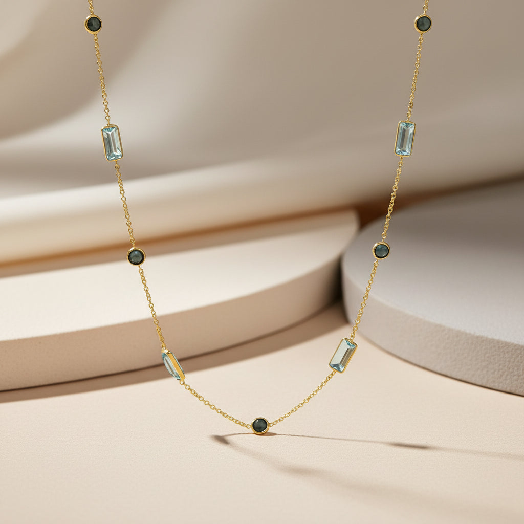 Zarte Gelbgoldkette mit hellblauen Topasen und London Blue Topasen in abwechselnder Zargenfassung, als Station-Collier entlang der Kette verteilt.