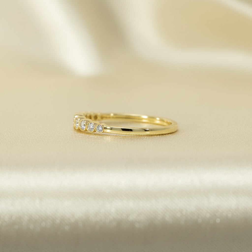 Seitliche Ansicht des Gelbgoldrings R57 mit flacher Schiene und Reihe zargen gefasster Brillanten im oberen Bereich.