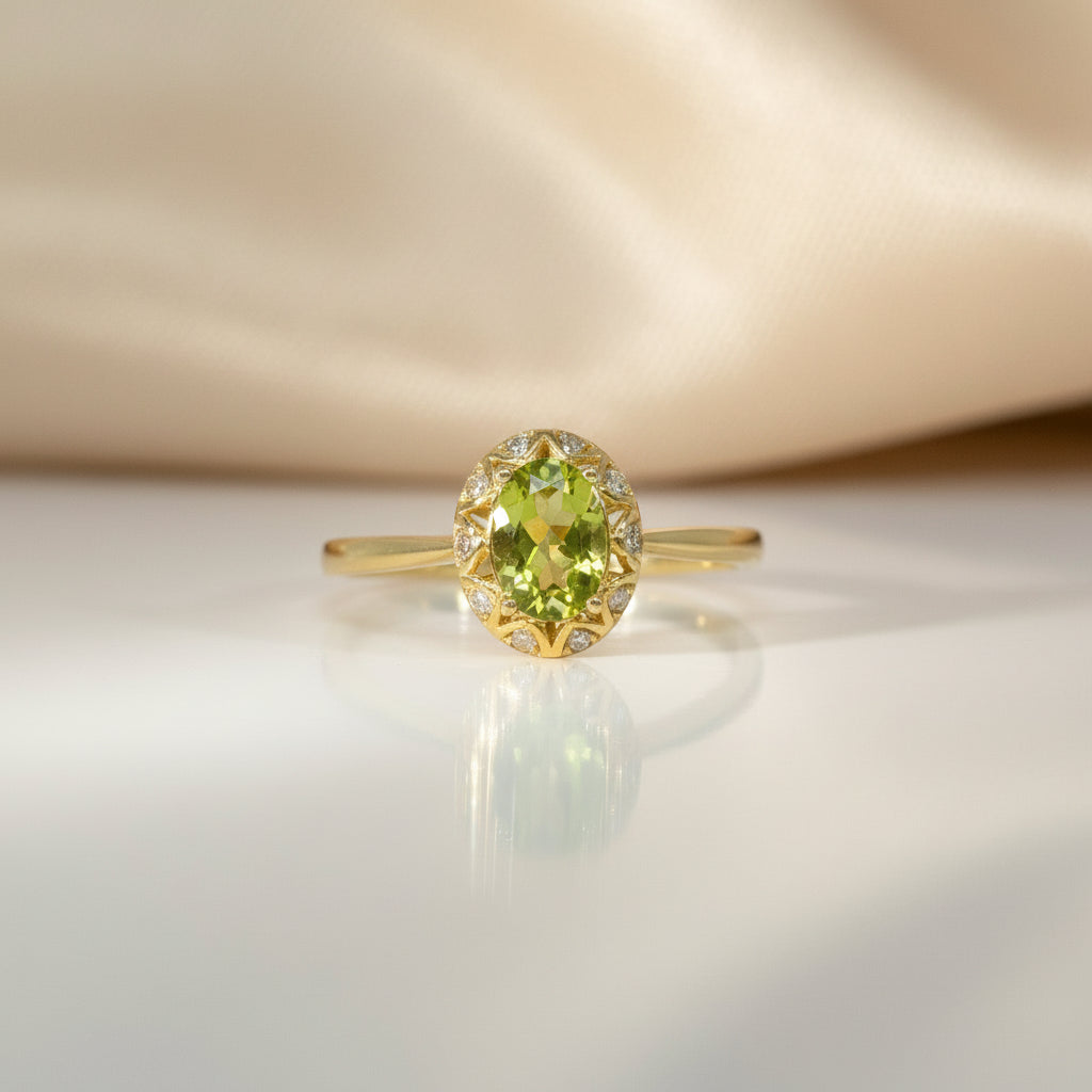 Feiner Gelbgoldring mit oval facettiertem Peridot als Mittelstein, umrahmt von kleinen Brillanten (zusammen 0,05 ct), frontal aufgenommen.