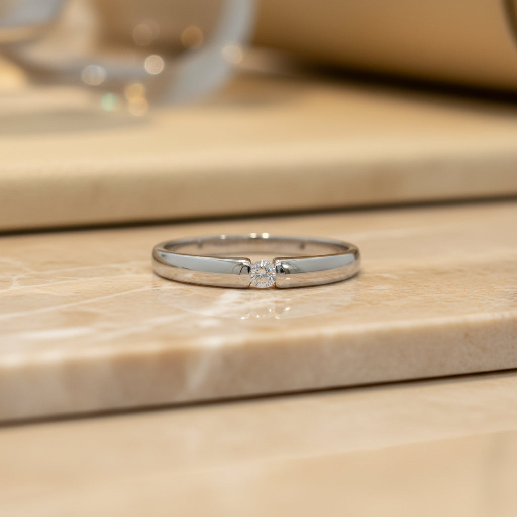 Schlanker Weißgoldring mit mittig gehaltenem Brillanten von 0,05 ct in moderner Spannoptik, frontal aufgenommen.