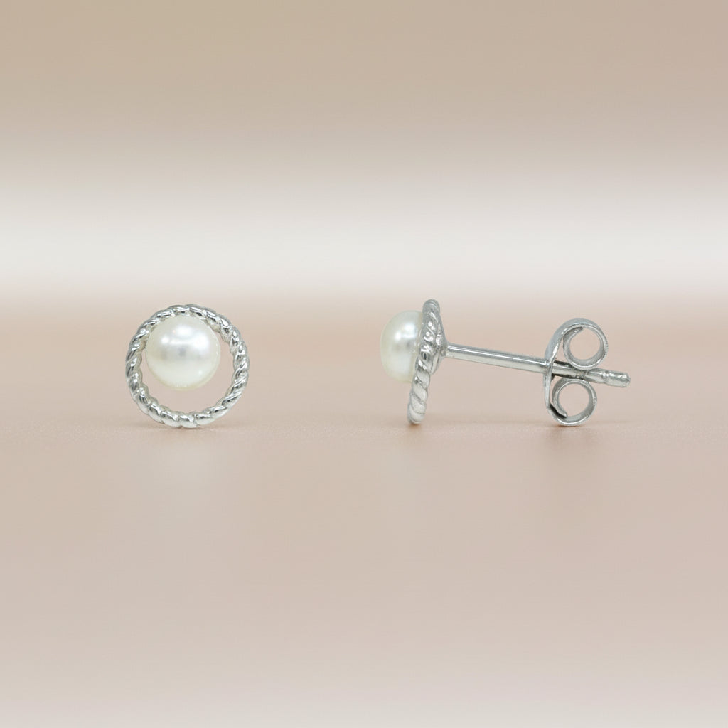 Silberne Ohrstecker mit einer zentralen Perle, umrahmt von einem gedrehten Kreis.