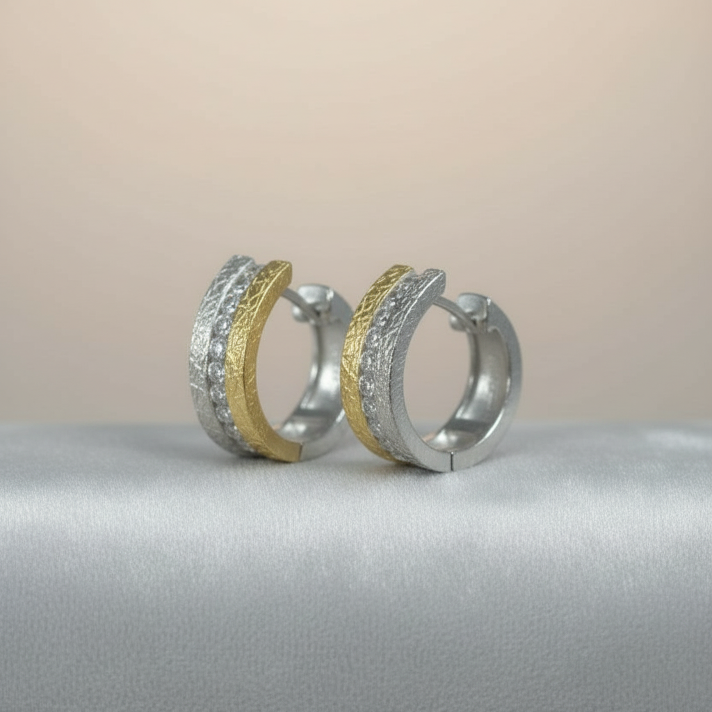 Splendido bicolor Silber-Creolen mit strukturierter Oberfläche und Zirkonia auf grauem Samtuntergrund.