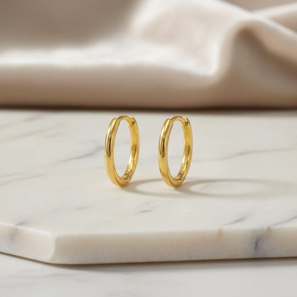 Kleine vergoldete Silbercreolen mit schmalem, hochglanzpoliertem Profil und 14 Millimetern Durchmesser.