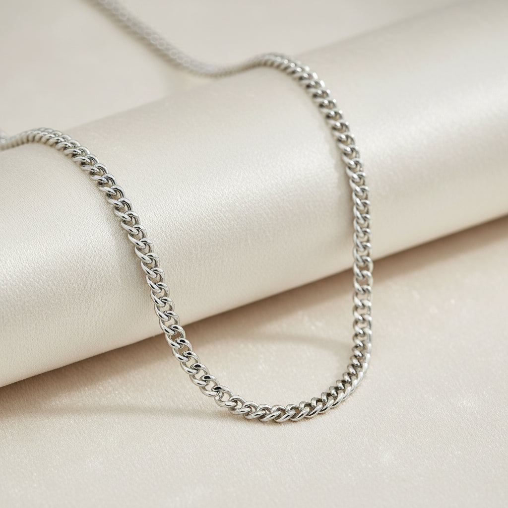 Silberfarbene Panzerkette mit flach anliegenden, eng verbundenen Gliedern vor weißem Hintergrund.