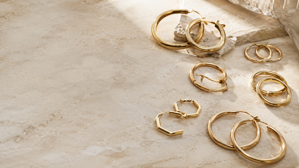 Frau mit goldenen Creolen am Ohr, warmes Studiolicht — Splendido Schmuck