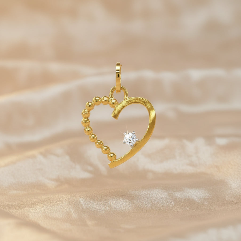 Herzförmiger Anhänger aus Gelbgold mit kugelstrukturierter und glatter Seite, verziert mit einem einzelnen Zirkonia-Stein.