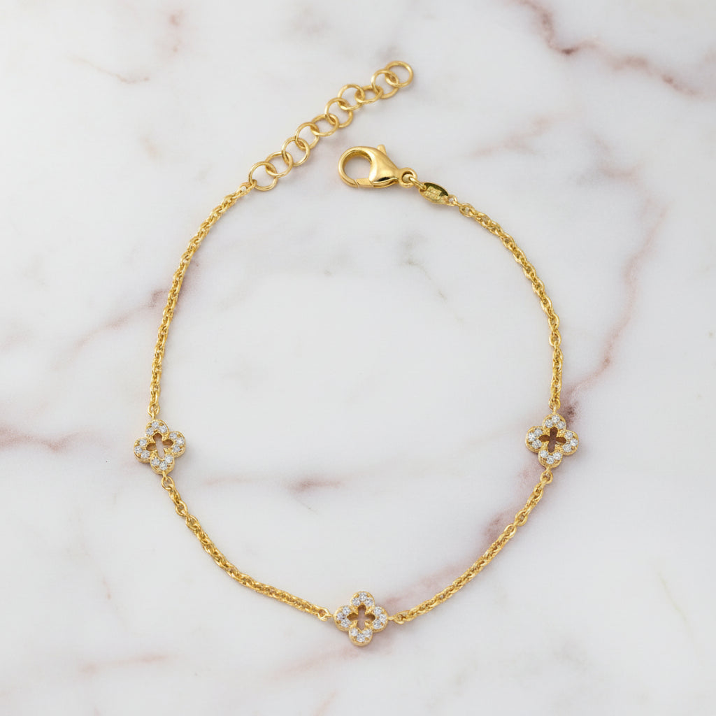Feines vergoldetes Armband aus 925er Silber mit drei kleinen Kleeblatt-Elementen, die rundum mit klaren Zirkonia-Steinen besetzt sind, plus Verlängerungskettchen und Karabinerverschluss.