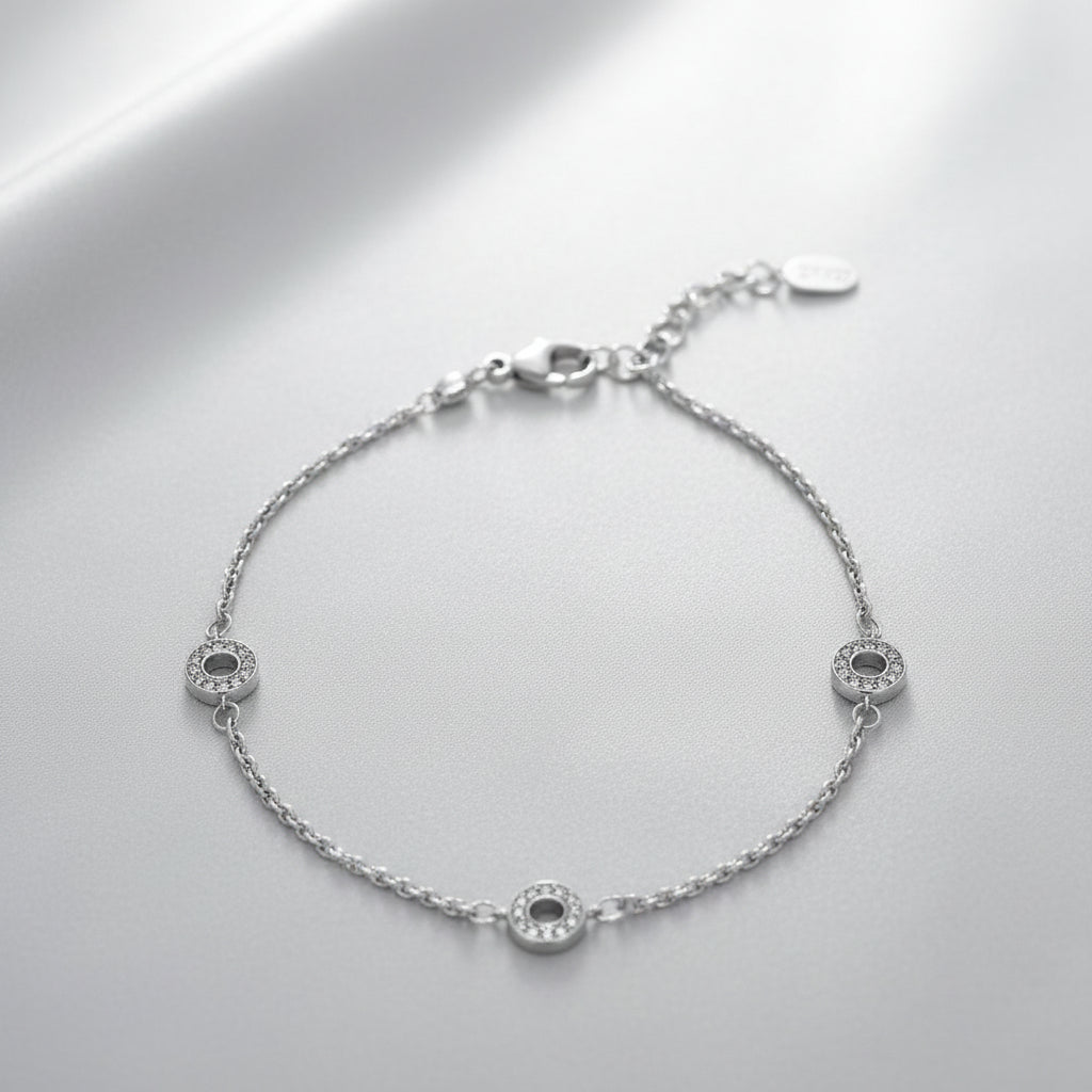 Feines Armband aus rhodiniertem 925er Silber mit drei runden Elementen, die umlaufend mit klaren Zirkonia-Steinen besetzt sind, plus Verlängerungskettchen und Karabinerverschluss.