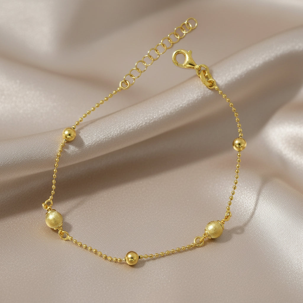 Feines Armband aus vergoldetem 925er Silber mit zarter Kugelkette und abwechselnd matt strukturierten und polierten Goldkugeln, mit Verlängerungskettchen und Karabinerverschluss.