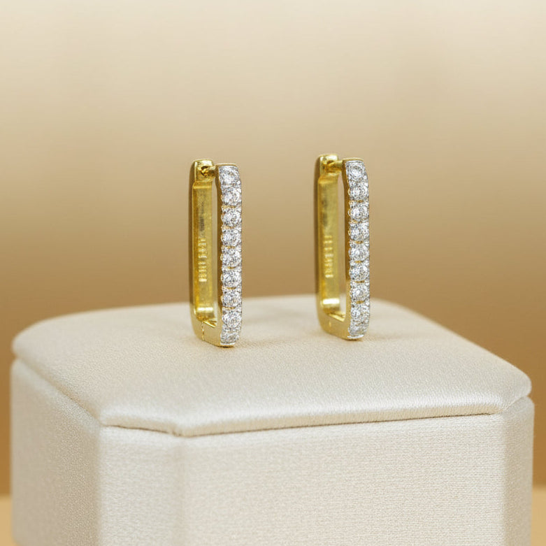 Rechteckige Creolen aus gelb vergoldetem 925er Silber mit einer Reihe klar funkelnder Zirkonia-Steine auf der Vorderseite.