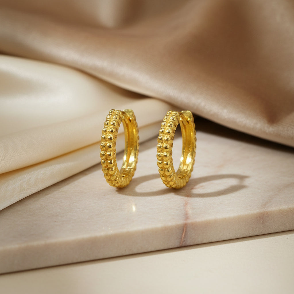 Rundliche Creolen aus gelb vergoldetem 925er Silber mit umlaufender Oberfläche im feinen Bead-Design.