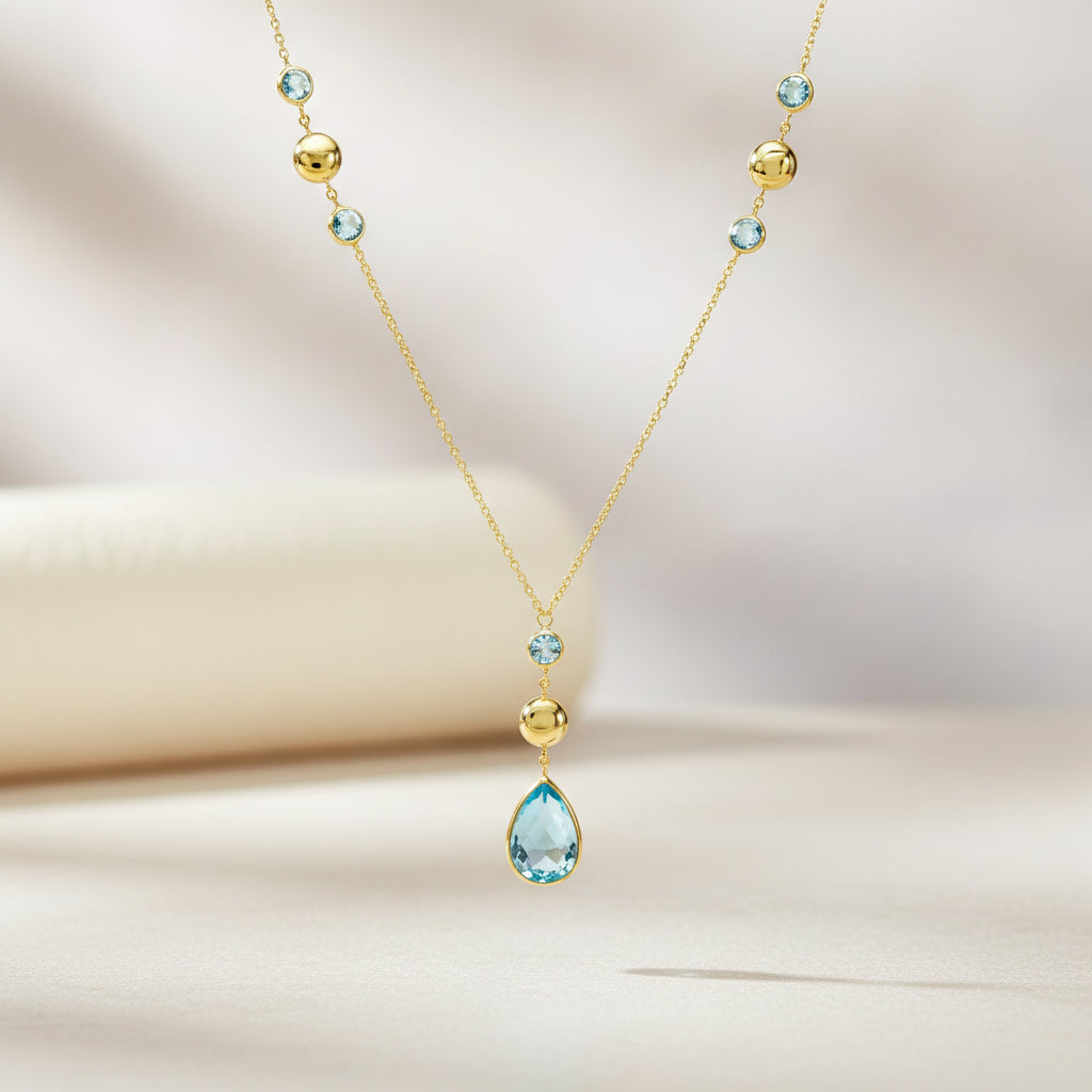 Kette aus Gelbgold mit rundem und tropfenförmigem Topas, London Blue Topas-Elementen und glatt polierten Zwischenelementen, komplett abgebildet.