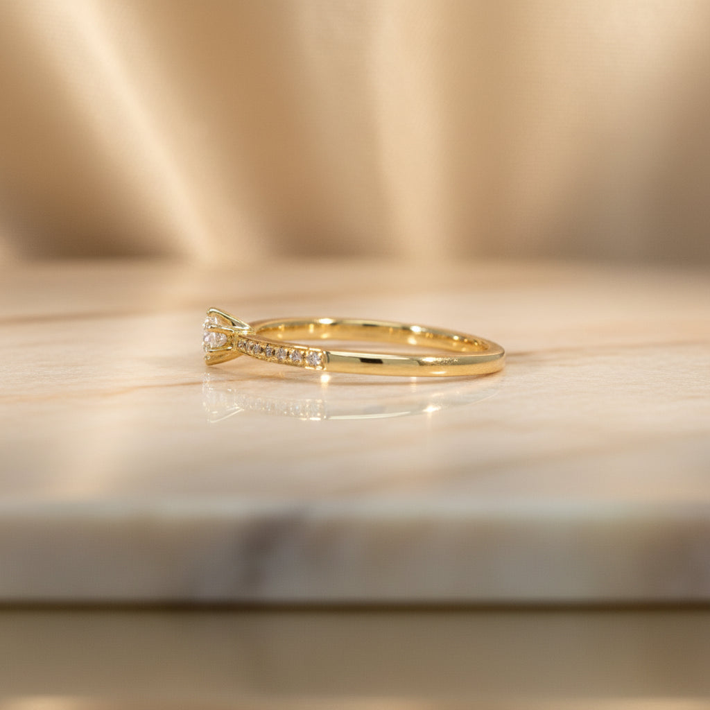 Gelbgoldring R30 seitlich fotografiert, der runde Mittelbrillant und die pavégefassten Diamanten sind gut sichtbar.