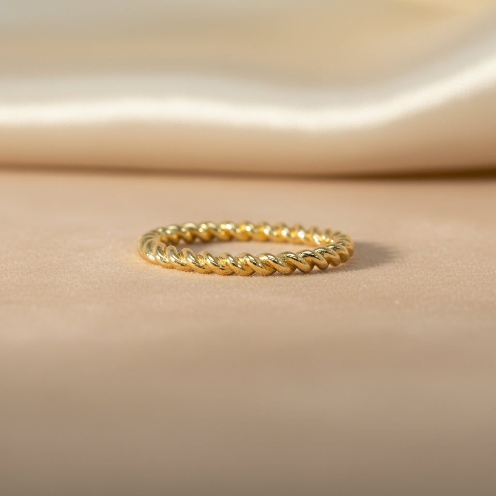 Schmaler Gelbgoldring im rundum gedrehten Kordel-Design, frontal auf hellem Hintergrund aufgenommen.