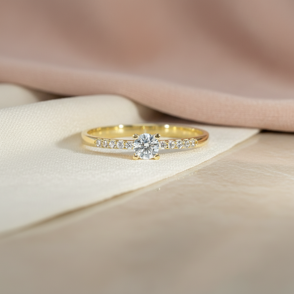 Schlanker Gelbgoldring mit mittig gefasstem rundem Zirkonia-Stein und zarter, halbseitig mit kleinen Zirkonias besetzter Schiene, frontal aufgenommen.