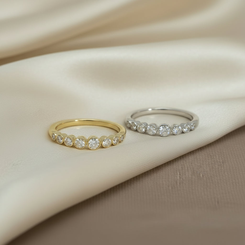 Schräg von vorne fotografierte R57-Ringe in Gelb- und Weißgold, die funkelnde Brillantreihe steht im Fokus.