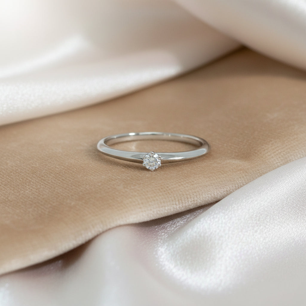 Zarter Weißgoldring mit rundem Brillantsolitär von 0,08 ct in klassischer Krappenfassung, frontal aufgenommen.