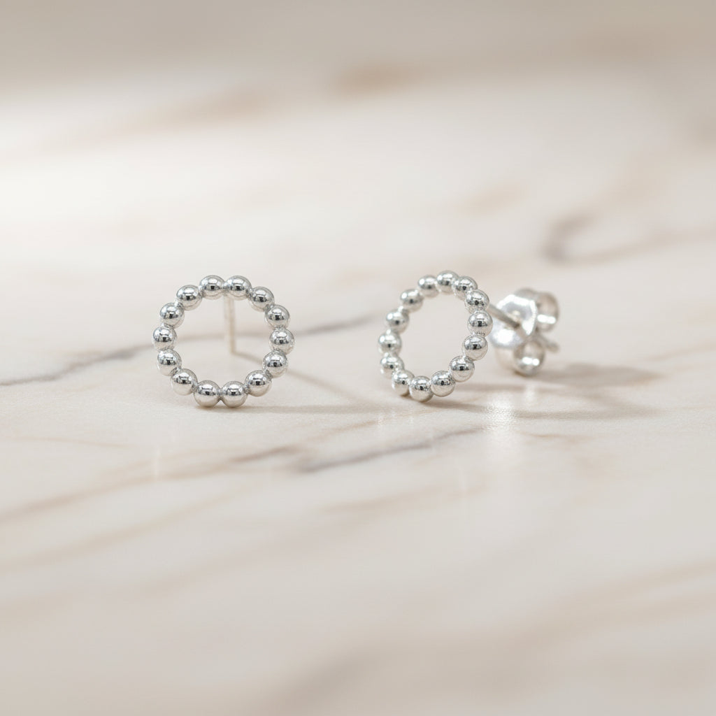 Silberne Ohrstecker in Form eines Kreises aus kleinen Kügelchen.

