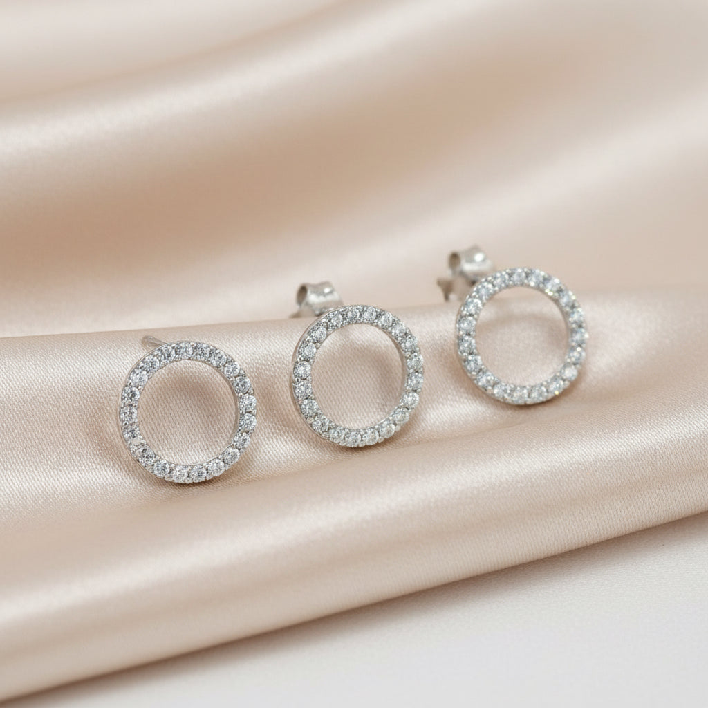 Silberne Ohrstecker in Form eines offenen Kreises, vollständig mit Zirkonia-Steinen besetzt.