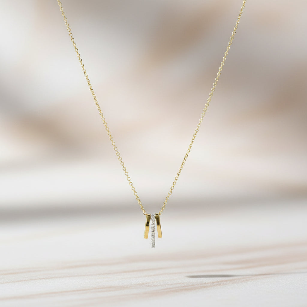 Seitliche Aufnahme einer goldenen Kette mit drei Anhängern, mittlerer Anhänger mit funkelnden Zirkonia