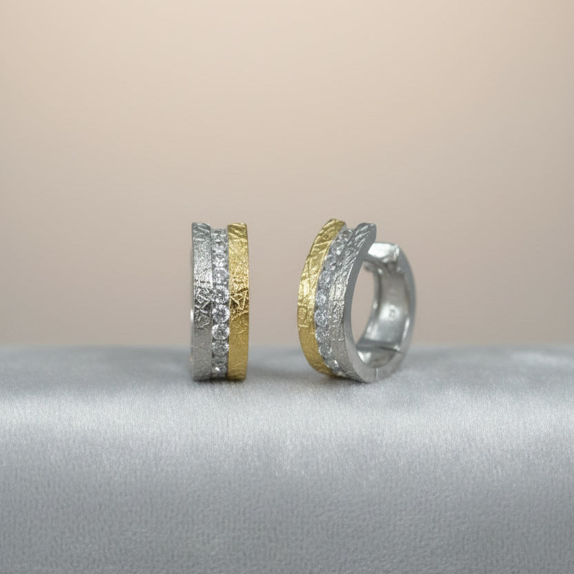 Splendido bicolor Silber-Creolen mit strukturierter Oberfläche und Zirkonia auf grauem Samtuntergrund.