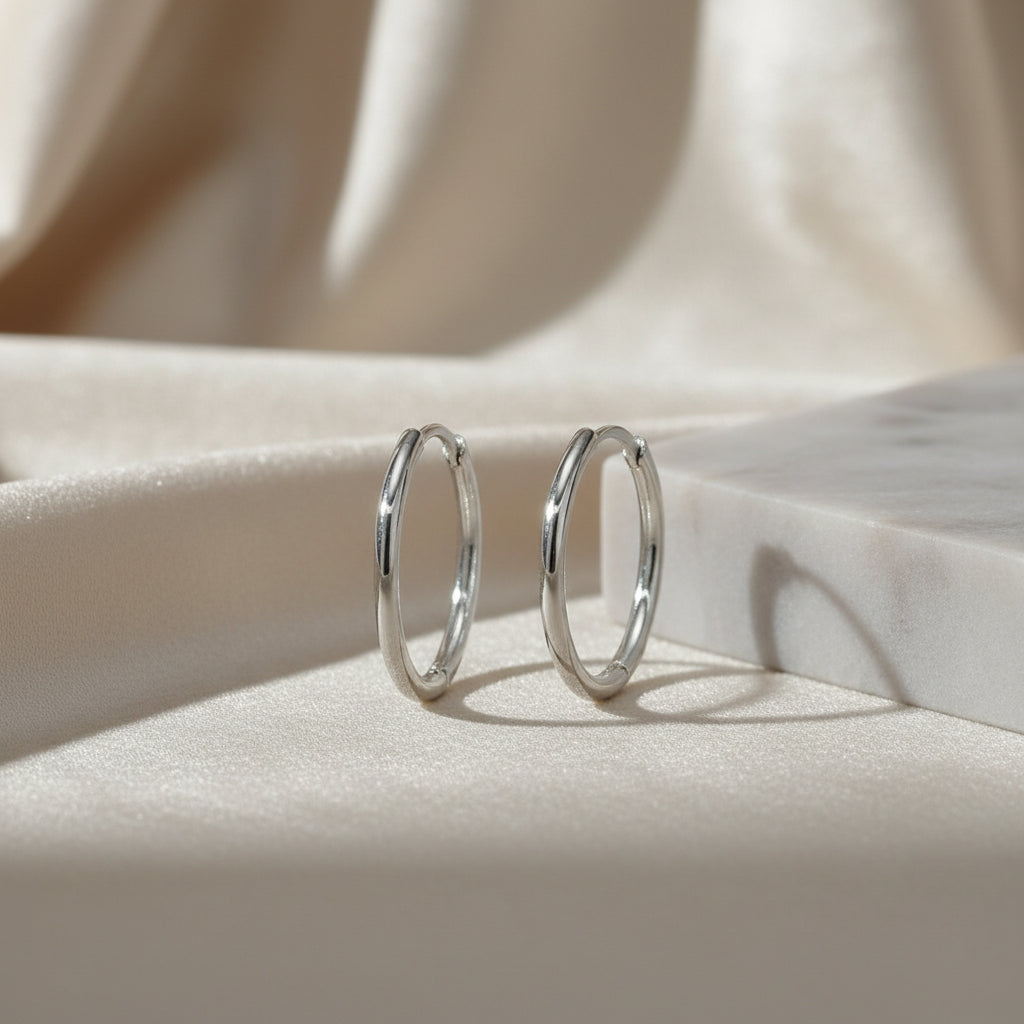 Zarte rhodinierte Silbercreolen mit schlankem, hochglanzpoliertem Rundprofil in 14 Millimetern Durchmesser.