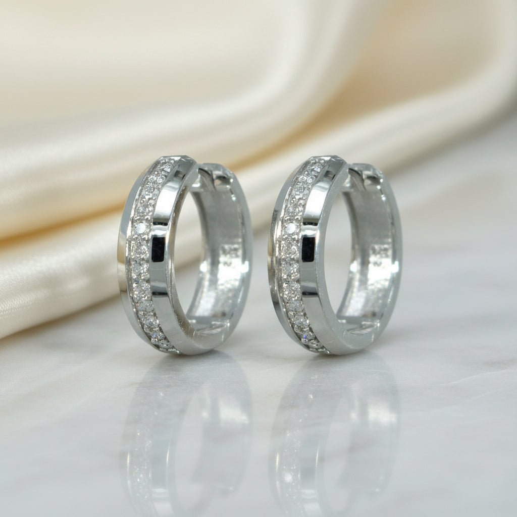 Breite rhodinierte Silbercreolen mit mittig verlaufender Reihe klarer Zirkonia-Steine.